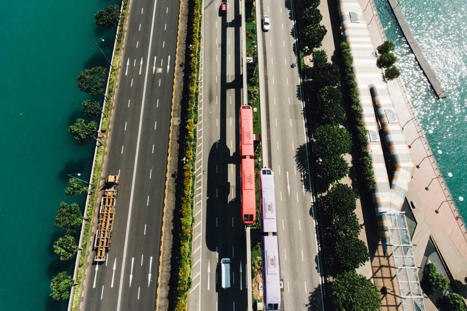 Aerial view of buses and traffic on a multi-lane road beside the water